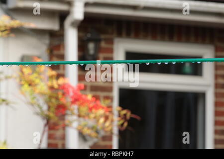 Zurück Garten mit Mauer und eine Wäscheleine mit Regentropfen Stockfoto