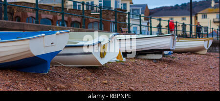 Kleine Fischerboote aufgereiht auf einem Kieselstrand in Sidmouth, England Stockfoto