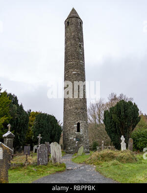 Ein Pfad führt durch einen alten Friedhof zu den Runden Turm an der Glendalough Klosteranlage in Wicklow, Irland Stockfoto