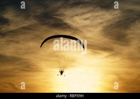 Paragliding bei Sonnenuntergang. Silhouette vor dem Hintergrund ein bewölkter Himmel Farben des Sonnenuntergangs. Stockfoto