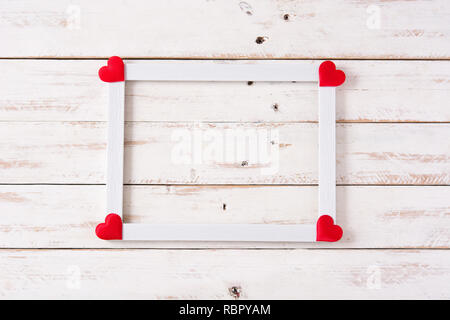 Das Mockup Valentinstag Konzept. Weißer Rahmen mit Herz auf weissem Holztisch eingerichtet. Copyspace Stockfoto