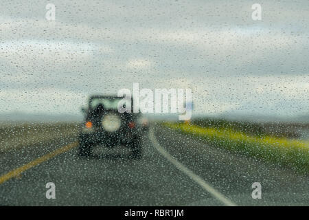 Regentropfen auf der Windschutzscheibe während der Fahrt auf der Autobahn an einem regnerischen Tag, Kalifornien Stockfoto