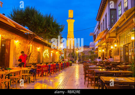 ANTALYA, Türkei - 9. Mai 2017: Die schmale Straße ist mit Terrasse des Restaurants gesäumt, die Gebrochenen Minarett des Kesik Minare Moschee gesehen o Stockfoto