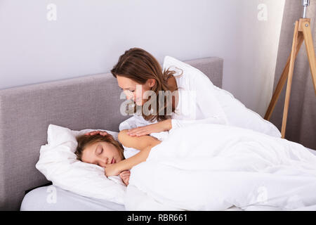 Reife Frau Aufwachen ihre Tochter schlief auf Bett im Schlafzimmer Stockfoto