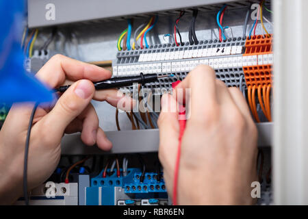 Nahaufnahme eines männlichen Elektriker Prüfung Sicherungskasten mit Multimeter Stockfoto