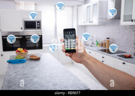 Nahaufnahme eines Menschen Hand mit Smart Home System Anwendung auf Mobilephone Stockfoto