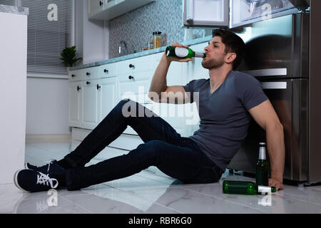 Seitenansicht des jungen Mannes, trinken Bier im Kühlschrank Stockfoto