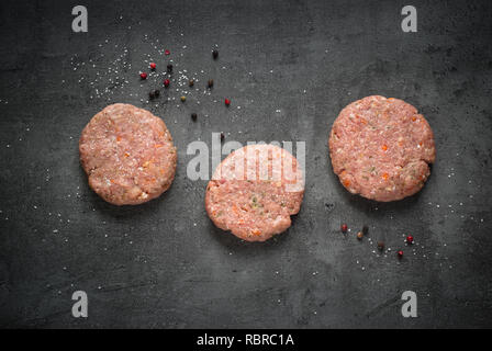 Schnitzel. Rohes Rindfleisch und Schweinefleisch Burger und Zutaten zum Kochen am Schiefer Hintergrund. Stockfoto