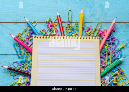 Leer Notebook und eine Vielzahl von Büromaterial auf einem blauen Schreibtisch aus Holz Stockfoto