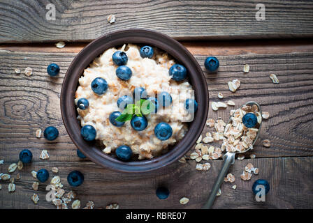 Haferflocken mit Heidelbeeren im rustikalen Holztisch. Flach. Stockfoto