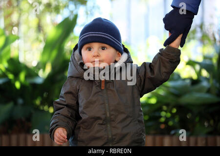 Close Up Portrait von Cute Baby Boy trägt einen blauen und grünen Hut Stricken Winter Winter Parka Stockfoto