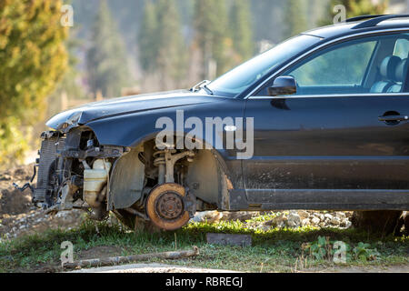 Alte verlassen Rusty gebrochen Papierkorb Auto nach einem Crash Unfall ohne Räder auf Holz Stempel bedeckt mit Schnee im Winter Tag draußen im Feld verlassen auf Stockfoto