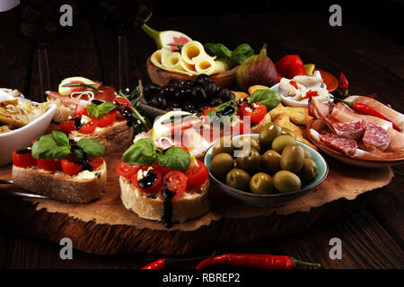 Italienische Antipasti Wein Snacks. Käsesorte, mediterrane Oliven, Gurken, Prosciutto di Parma, Tomaten, Artischocken und Wein in Gläsern auf Registerkarte Stockfoto