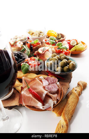 Italienische Antipasti Wein Snacks. Käsesorte, mediterrane Oliven, Gurken, Prosciutto di Parma, Tomaten, Artischocken und Wein in Gläsern auf Registerkarte Stockfoto