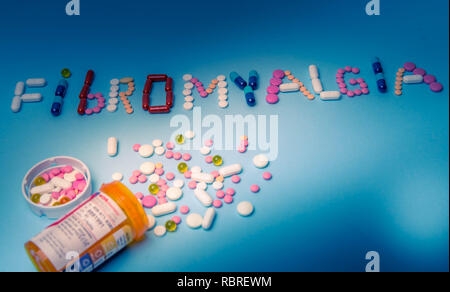 Das Wort Fibromyalgie von bunten Medikamente, Pillen, Drogen, Tabletten, Kapseln auf einem blauen Hintergrund Stockfoto