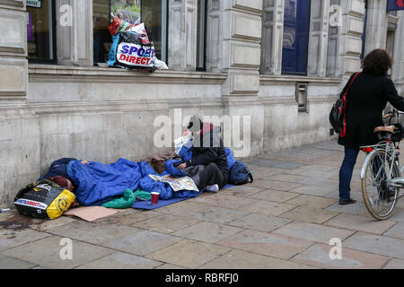 Ein obdachloser Mann gesehen, schlafen auf einem Bürgersteig in Piccadilly Circus. Stockfoto