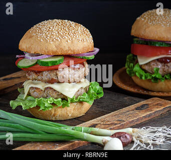 Burger mit zwei gebratene Koteletts, Käse und Gemüse in einer Runde Weizenmehl bun Stockfoto