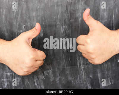 Mann zeigt Daumen hoch gegen Schwarze Brett Hintergrund Stockfoto