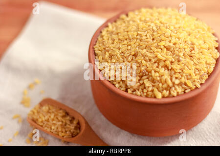Raw Bulgur in einem Ton Schüssel auf Holzbrett Stockfoto