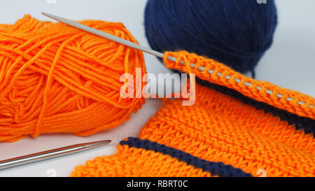 Gestrickte Stück orange und blau Wolle mit Stricknadeln Stockfoto