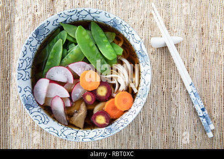 Füllen Schüssel mit Udon Noodle Soup Serie Bild 7: Schale mit Nudeln, Shiitake-Pilze, Zuckerschoten, Brühe, Radieschen und Karotten Stockfoto