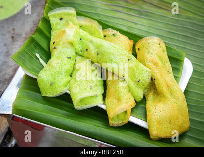 Süße Nachspeise mit Kokosmilch und schwarzem Sesam gerollt Wafer grün auf Banana leaf für Verkauf Street Food-Thong Muan Sod Soft Thai Coconut Crepes Stockfoto