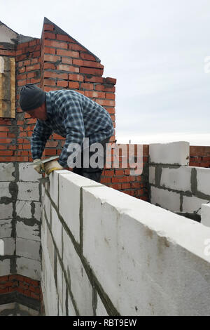 Mit Hilfe eines glutenhaltigen Lösung, der Arbeiter eine Mauer errichtet von Gas Bausteine 2018 Stockfoto