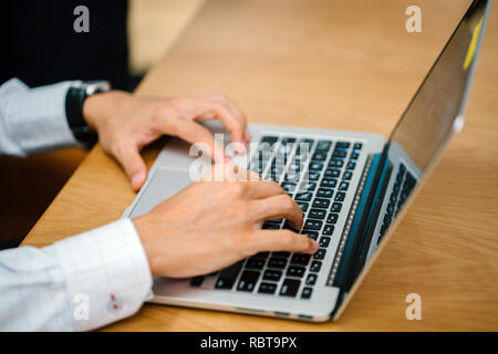 Nahaufnahme von einem Paar Hände schreiben auf einem Laptop. Ein Geschäftsmann Arten auf seinem Laptop Computer und sein Kollege ist eng hinter stehen. Stockfoto