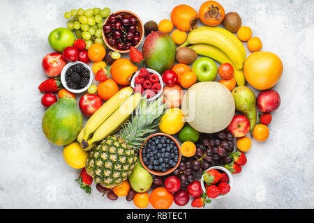 Herz aus gesunden rainbow Früchte, Erdbeeren Himbeeren orangen Pflaumen Äpfel, Kiwis, Weintrauben, Heidelbeeren mango Kaki Ananas auf Weiß Stockfoto