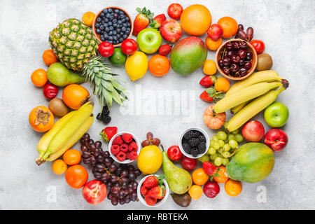 Rainbow Früchte Hintergrund Rahmen, Pflaumen Erdbeeren Himbeeren Orangen, Äpfel, Kiwis, Weintrauben, Heidelbeeren mango Kaki auf weißem Tabelle, Ansicht von oben Stockfoto