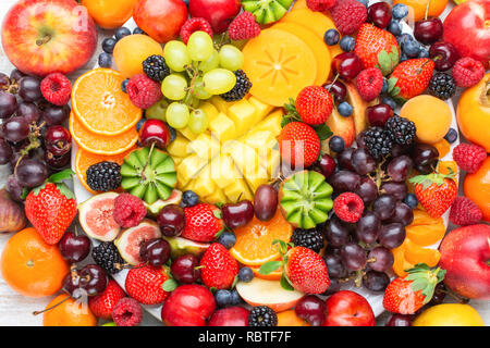 Gesunde Obstteller Hintergrund Pflaumen Erdbeeren Himbeeren, Orangen, Äpfel, Kiwis, Weintrauben, Heidelbeeren mango Kaki, Ansicht von oben, Stockfoto