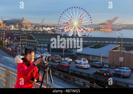 Seattle, Washington, USA. 11 Jan, 2019. Eine Frau nimmt Fotos während der letzten Sonnenuntergang über die alaskische Weise Viaduct am Pike Place MarketFront. Die Autobahn permanent geschlossen um 10:00 Uhr Am 11. Januar so Crews bewegen kann der State Route 99 vom Viadukt zu einem state-of-the-art Tunnel. Die 1950er-Ära Doppeldecker Autobahn stark im Jahr 2001 Nisqually Erdbeben beschädigt wurde und hat lange über seine Nutzungsdauer gepflegt wurde. Ein zwei Kilometer langer, gelangweilt Straßentunnel ersetzt die alaskische Weise Viaduct, die State Route 99 in der Innenstadt von Seattle aus der SODO Nachbarschaft zu South Lake Union. Gutschrift: Stockfoto