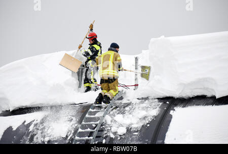 12 Januar 2019, Bayern, Schönau am Königssee: Feuerwehrmänner der Schnee vom Dach eines Skilift Talstation der Jennerbahn. Foto: Tobias Hase/dpa Stockfoto
