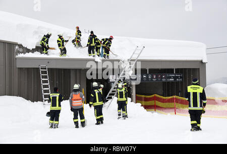 12 Januar 2019, Bayern, Schönau am Königssee: Feuerwehrmänner der Schnee vom Dach eines Skilift Talstation der Jennerbahn. Foto: Tobias Hase/dpa Stockfoto