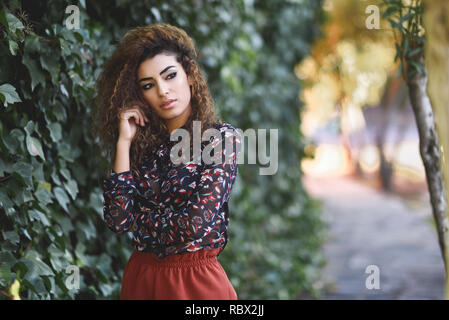 Schöne junge arabische Frau mit schwarzen Locken Frisur. Arabische Mädchen legere Kleidung auf der Straße. Stockfoto