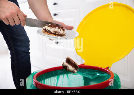 Nahaufnahme einer Hand werfen Kuchen In Papierkorb Stockfoto