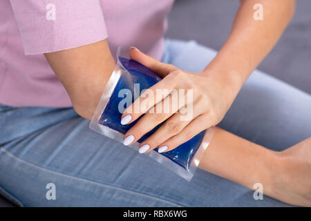 Nahaufnahme von einer Frau, die Hand mit Eis Gel Pack auf Arm Stockfoto