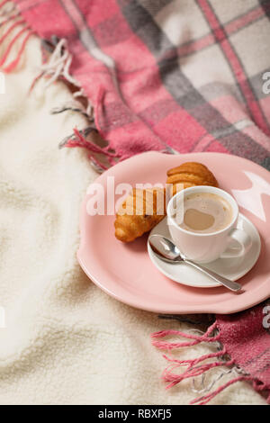 Winter. Ein sehr warmes Rosa Decke und einer Tasse Kaffee und Croissants auf dem Bett. Selektive konzentrieren. Stockfoto