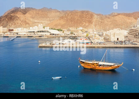 Muscat, Oman - November 1, 2018: traditionellen omanischen Boot (dhau) im Hafen von Mutrah in Muscat und im Hintergrund der Fischmarkt und die Corniche Stockfoto
