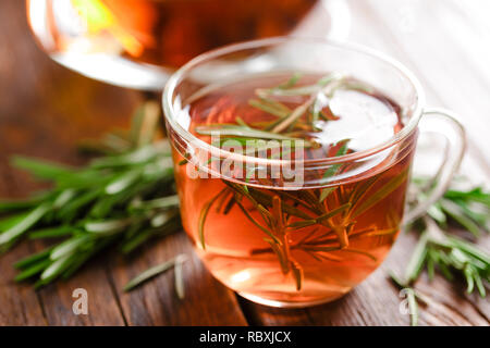 Rosmarin Tee im Glas Tee Tasse auf rustikalen Holztisch Nahaufnahme. Pflanzliche vitamin Tee. Stockfoto
