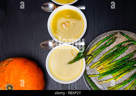 Hausgemachte grüne Cremesuppe mit Spargel, grüne Erbsen, Kürbis, Garnelen auf hölzernen Hintergrund Stockfoto
