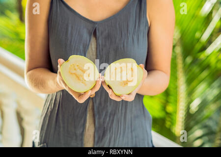 Guave in schöne weibliche Hände auf grünem Hintergrund. Stockfoto