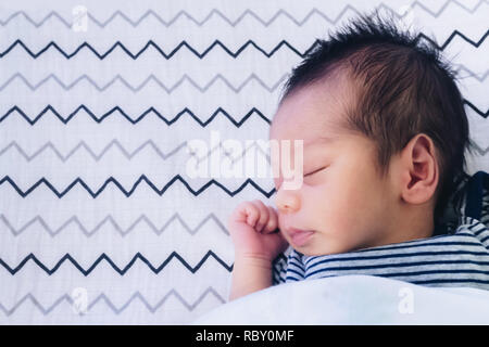 Nahaufnahme der niedlichen kleinen Neugeborenen asiatischen Baby schlafend auf dem Bett im Kinderzimmer mit kopieren. Familie, gesund, Leben und Beziehung Konzept. Stockfoto