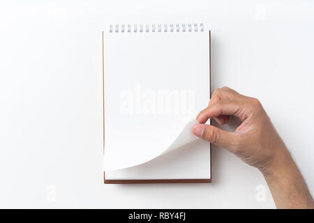 Designkonzept - Perspektivische Ansicht braun hardcover Spirale notebook, Hand des Menschen flip curl Seite auf Hintergrund für Mockup isoliert Stockfoto