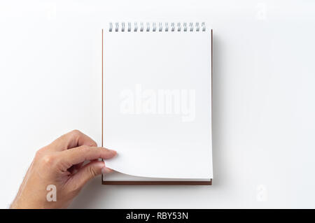 Designkonzept - Perspektivische Ansicht braun hardcover Spirale notebook, Hand des Menschen flip curl Seite auf Hintergrund für Mockup isoliert Stockfoto