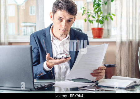 Man agent Holding ein Auto Spielzeug und Dokumente, die für die Registrierung von Autos im Büro. Das Konzept der Kauf Verkauf und Vermietung von Transport Stockfoto