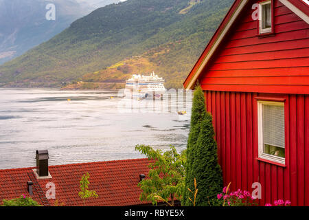 Flam, Norwegen - 31. Juli 2018: Norwegischen Fjord Sognefjord Landschaft, roten Holzhaus und Aidaluna Kreuzfahrtschiff Stockfoto