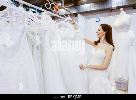 Frau in einem Hochzeitskleid Verschraubung an der Hochzeitsmesse. Präsentiert Szene mit einem Modell aus der Messestand. Essen, Nordrhein-Westfalen, Deutschland, Eur Stockfoto