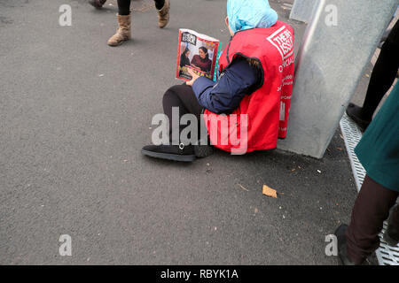 Eine ältere Frau grosse Ausgabe Magazin Anbieter sitzen auf dem Bürgersteig Verkauf Zeitschriften Meghan Markle an der vorderen Abdeckung in London England UK KATHY DEWITT Stockfoto