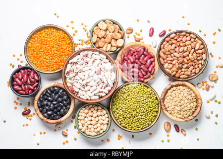 Hülsenfrüchte, Linsen, Bohnen und chikpea Sortiment in verschiedenen Schüsseln auf weißen Tisch Ansicht von oben. Stockfoto